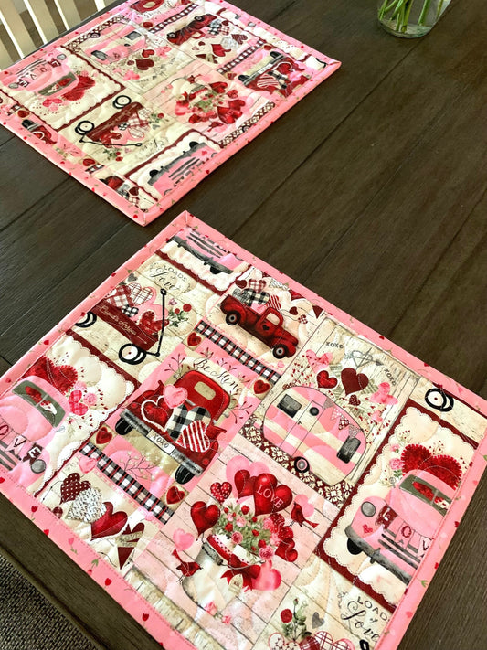 Pink and red Valentine place mats featuring hearts, balloons, wagons and trucks.